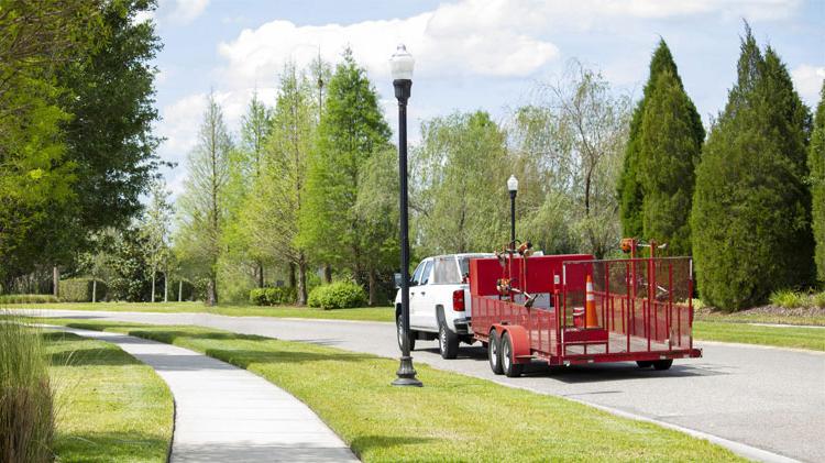 A lawn utility trailer driving down a residential road.